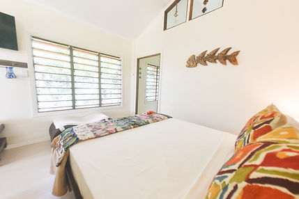 Bedroom with bed, pillows, window, door, and decorative fish. Gecko Digital Fiji