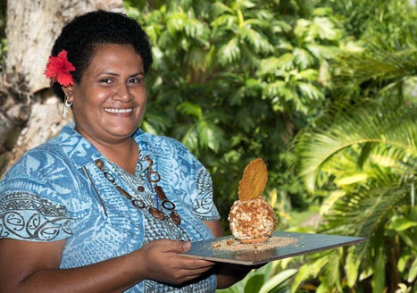 Smiling woman holding decorated dessert on tray against green background.