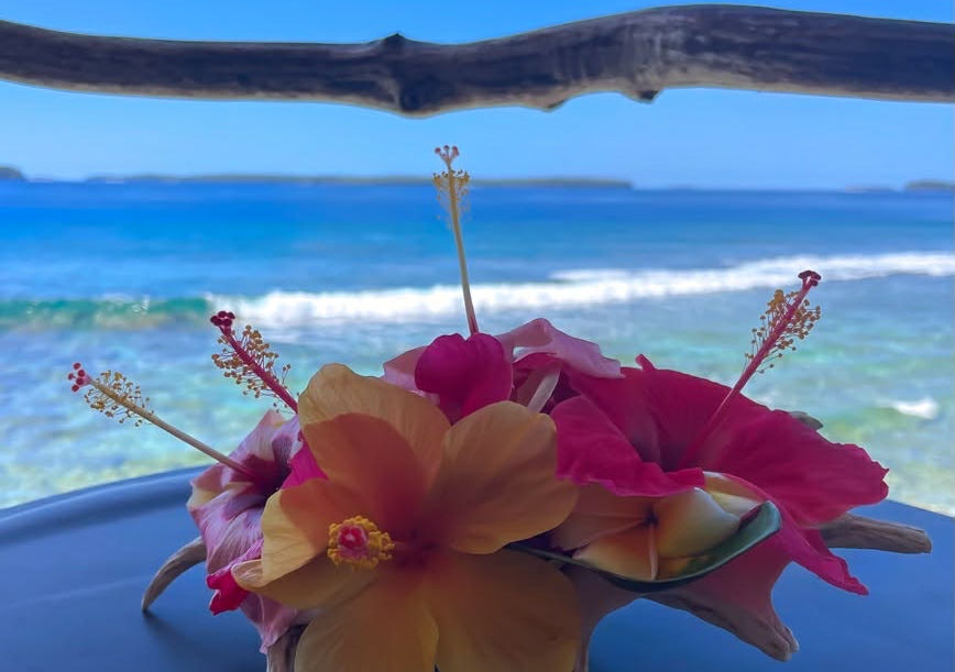 Conch shell centerpiece with colorful hibiscus flowers overlooking a tropical ocean view.