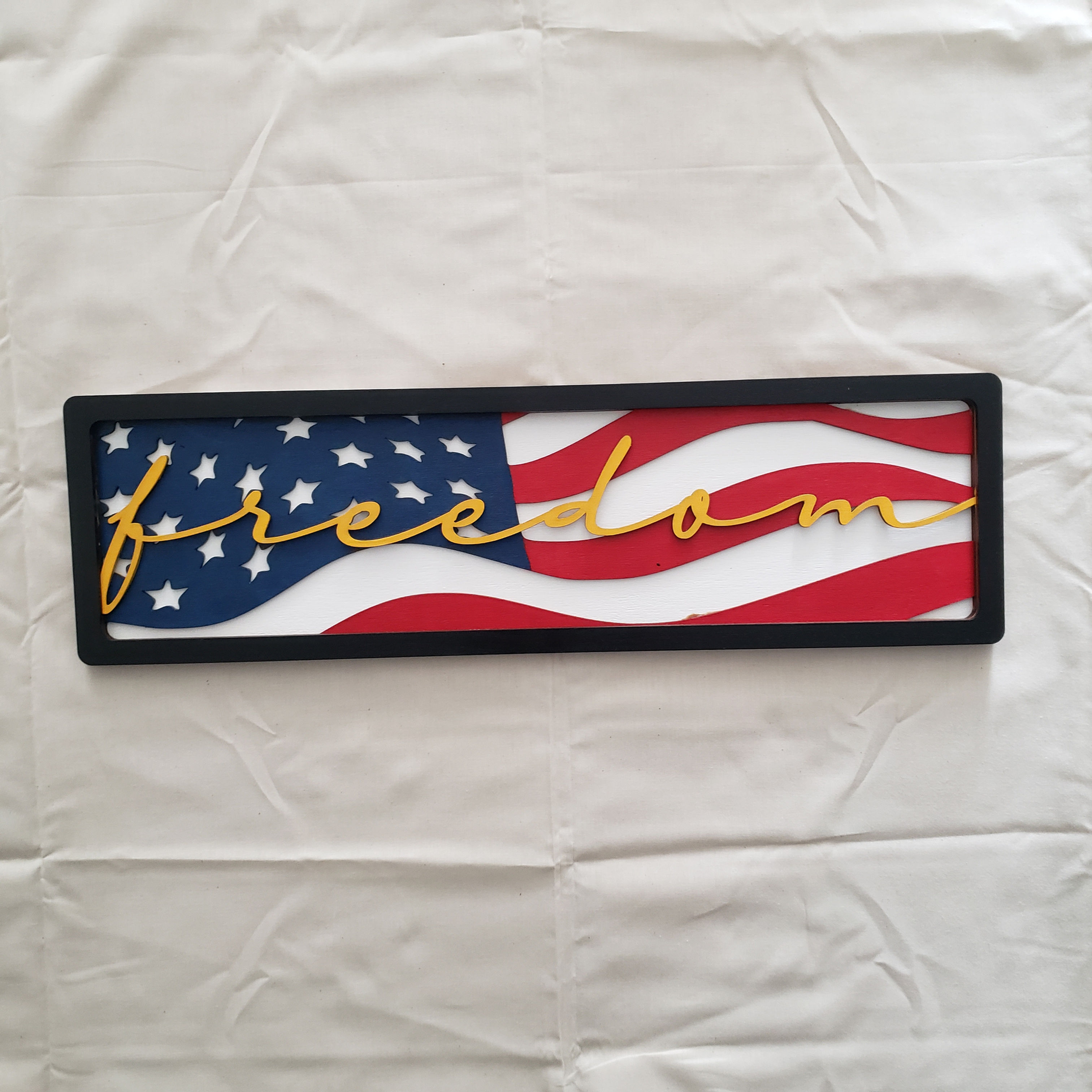 American Flag art with the word freedom in gold cursive letters.