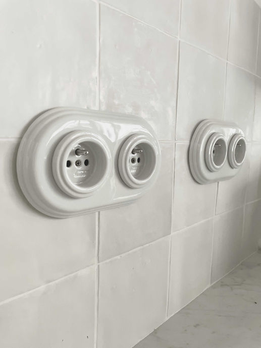 alt="dans cette cuisine les matériaux de qualité ont été privilégiés comme ces prises en céramique ou ces carreaux blancs en terre cuite"