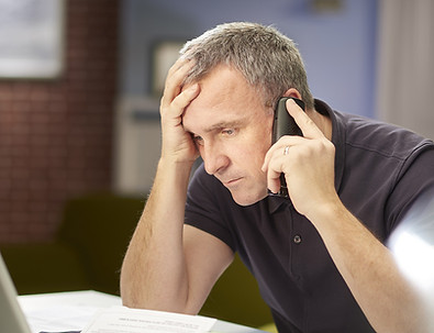 a mature man sits at his dining table at home looking through some bills and paperwork , w
