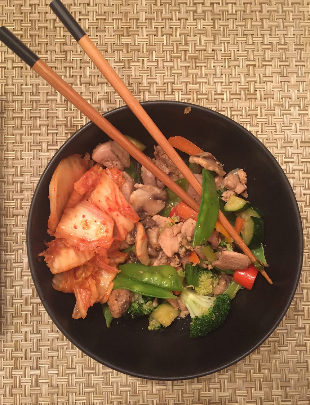 plate of chicken stir fry with mixed vegetables chop sticks kimchi