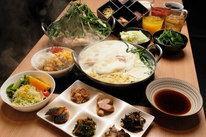 桌上陳列多道美食,有熱鍋涮菜、泡沫湯麵、壽司、生菜沙拉,以及多色飲料,食物香氣四溢,環境溫馨