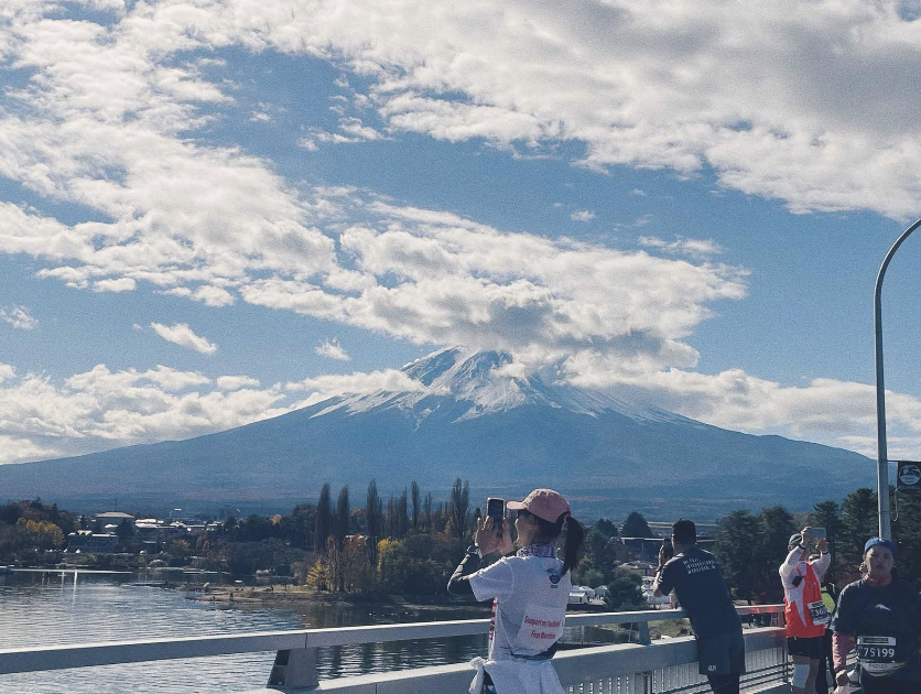 藍天白雲、富士山前有多位跑者在拍照