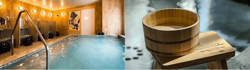 室內溫泉,左側是石質浴池,牆壁和天花板為木色,右側有木質桶和凳子,上面有英文文字,環境舒適寧靜