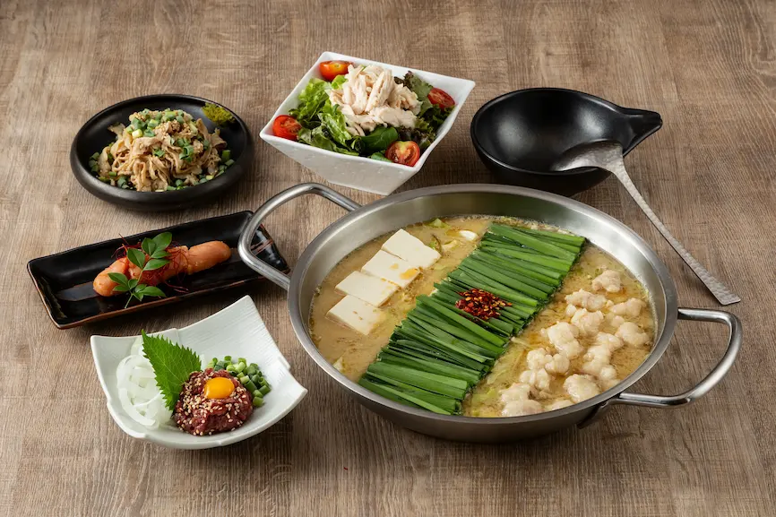 木桌上放著日本料理,有牛肉、蔬菜沙拉、豆腐及火鍋,顏色豐富,整體擺盤精緻,呈現出溫馨的用餐氛圍