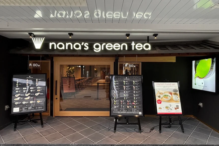 一家名為nana's green tea的餐廳門面,展示牌上有菜單和餐點圖片,裝飾現代簡約,整體氛圍溫馨
