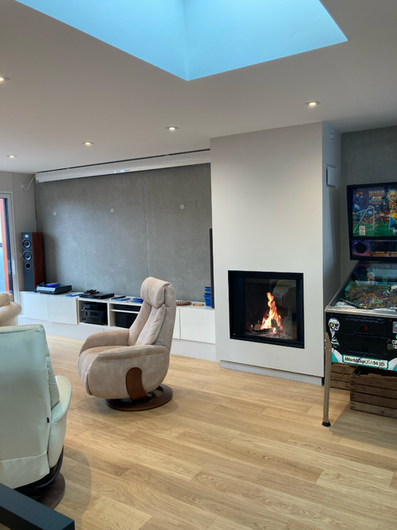 Cheminée Stûv µM (MicroMega) à vitre escamotable : la vitre coulisse pour permettre le fonctionnement en feu ouvert, puis s'abaisse pour profiter de la performance d'un foyer fermé. 
Grâce à sa chambre courbe, les bûches sont disposées verticalement.