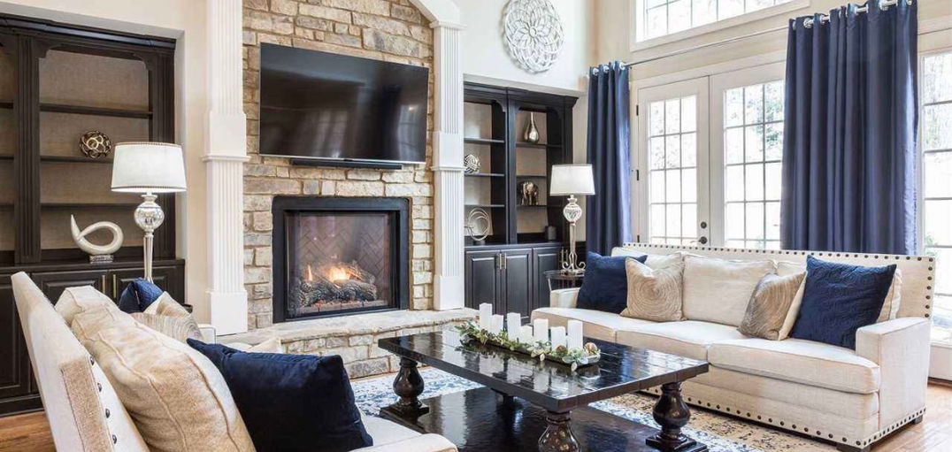 Living room interior design in Raleigh, NC with stone fireplace, built-in shelving, and neutral seating.