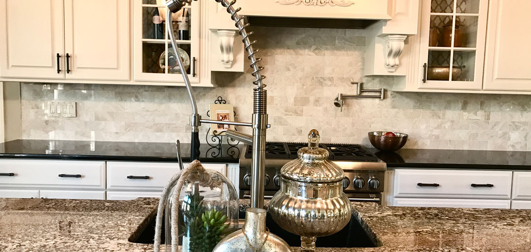 Kitchen remodel in Raleigh, NC with marble backsplash, pot filler, creamy white cabinets, and a commercial faucet.