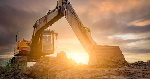 A JCB digger is digging the ground with the sun in the background