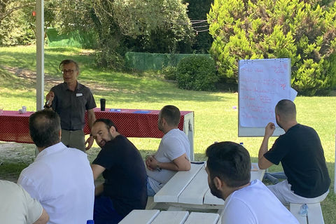 outdoor bir mekanda yaşayarak öğrenme eğitimi sonrası eğitmenle bir araya gelmiş ekip öz değerlendirme yapıyor