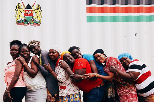 Women in Kenya helped by Project Três hug and smile at the camera