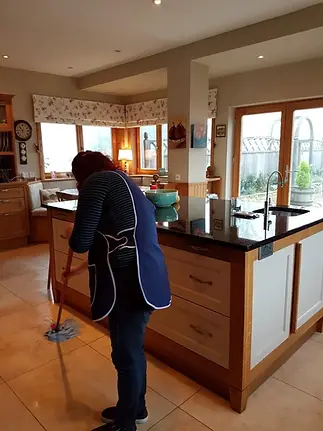 A cleaner mopping a domestic property, specifically the kitchen.