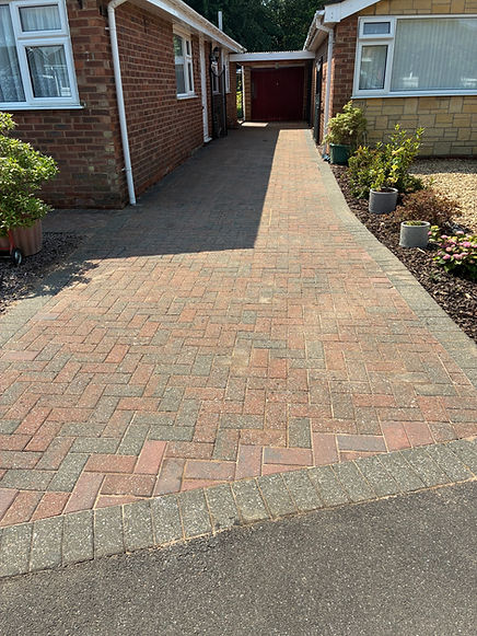 Residential brick paver driveway partially pressure washed, showing clean and dirty sections