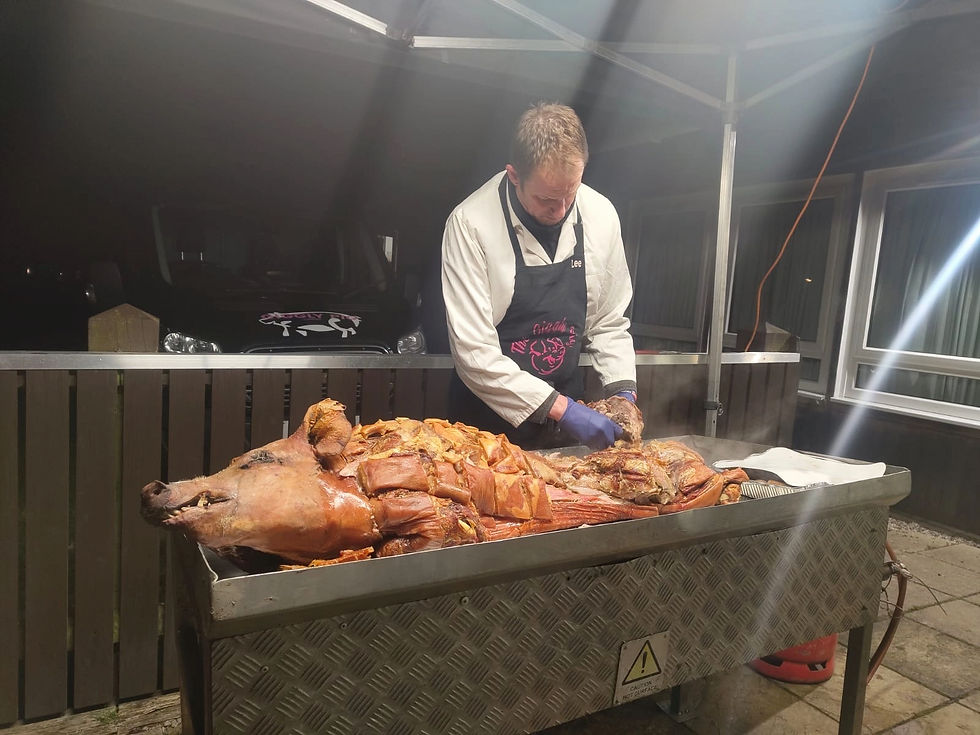 A worker for The Giggly Pig standing over a hog roast.