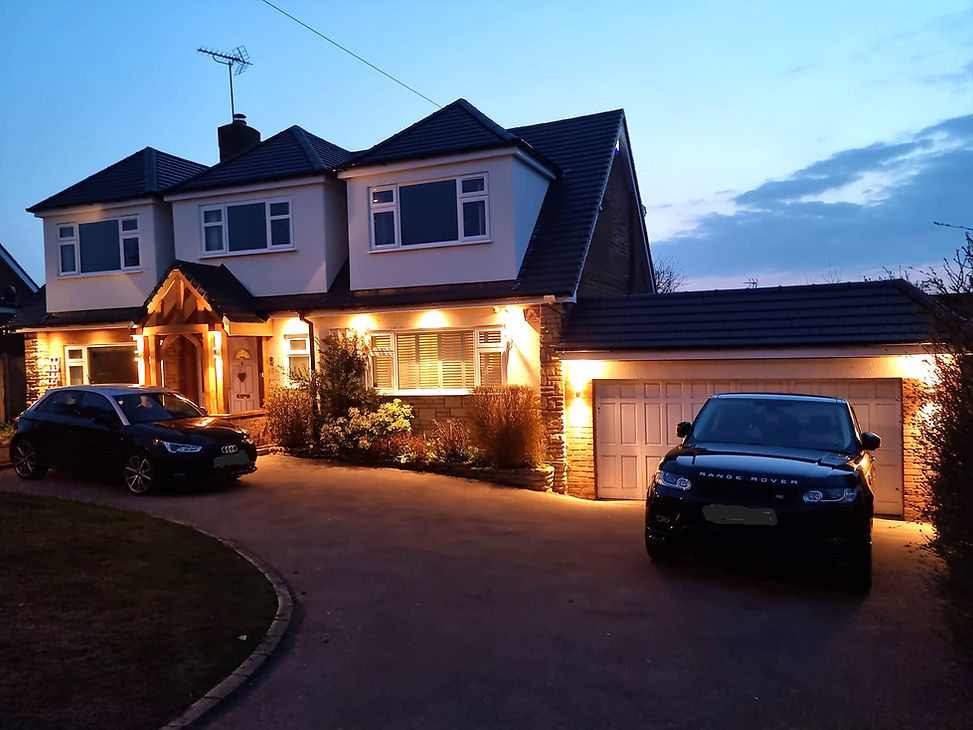 The outside of a house, lit in the dark by outdoor lighting