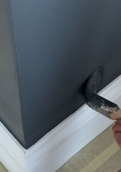 paint brush applying black paint to a wall