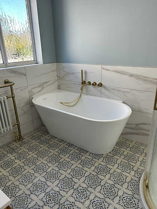A bathroom with a bath, radiator, and tile flooring