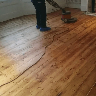 A sanding device being used on a wooden floor.
