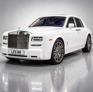 White luxury Rolls Royce Phantom saloon car with custom LES RR number plate parked on reflective showroom floor