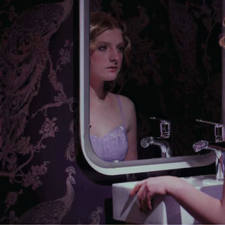 A woman looking into the mirror in a bathroom set.