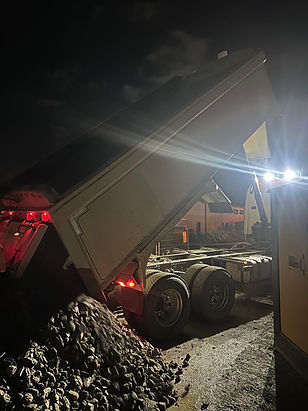 A large dump truck with raised bed in a dimly lit industrial area