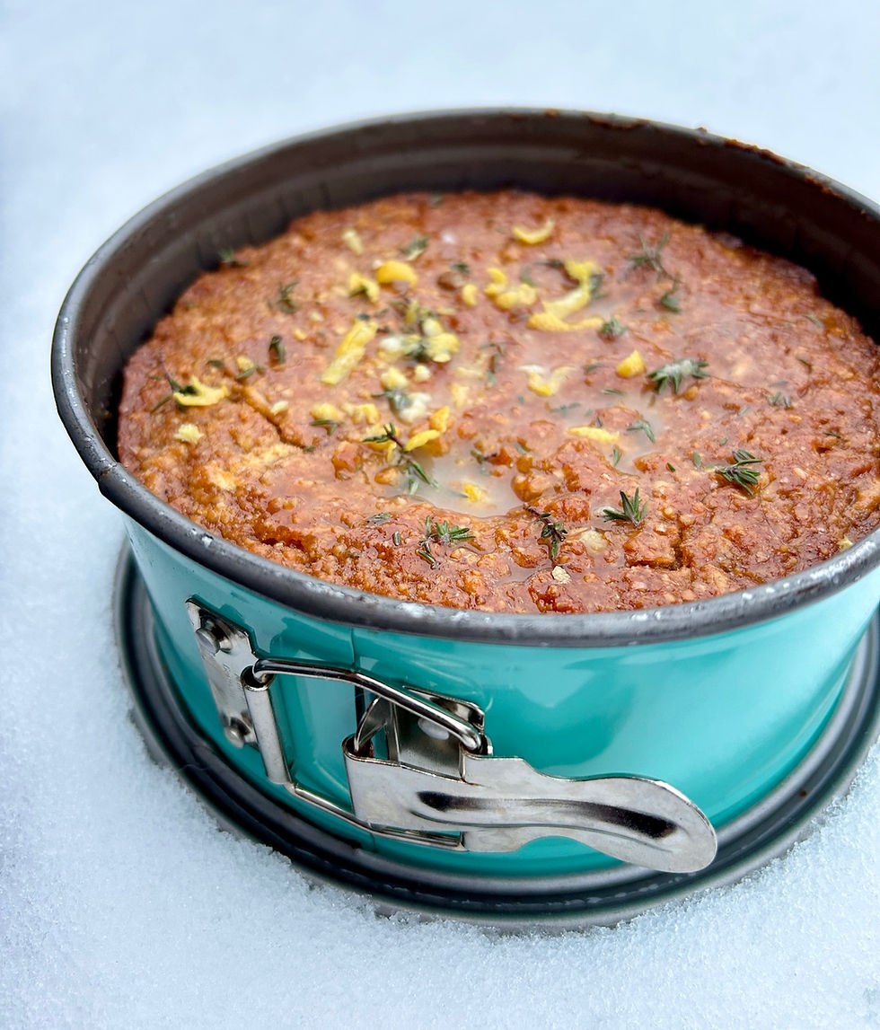 Veganer Zitronen-Thymian-Kuchen in kleiner Springform, frisch gebacken, mit Zitronenzeste und Thymian dekoriert, fotografiert im Schnee