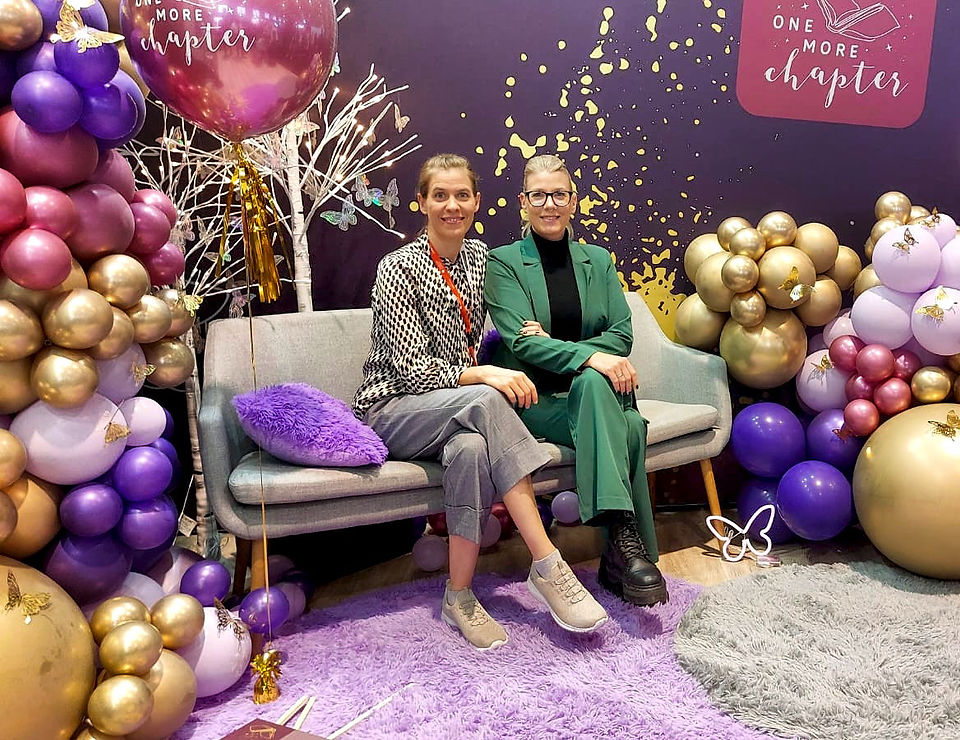 Lena Dieterle und Hörbuchsprecherin Lisa Dietrich auf der Buchmesse auf einem Sofa mit bunten Luftballons