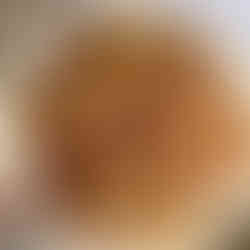 Mehrere frisch gebratene, goldbraune Zucchini-Kartoffelpuffer auf einem hellen, runden Teller – angerichtet in einer leicht überlappenden Schichtung, bereit zum Servieren.