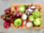 Zutaten für veganen Zwiebelkuchen auf einem Holzbrett: rote Zwiebeln, grüne Tomaten, Weintrauben, Chili, Walnüsse und Kürbiskerne in der Vorbereitung