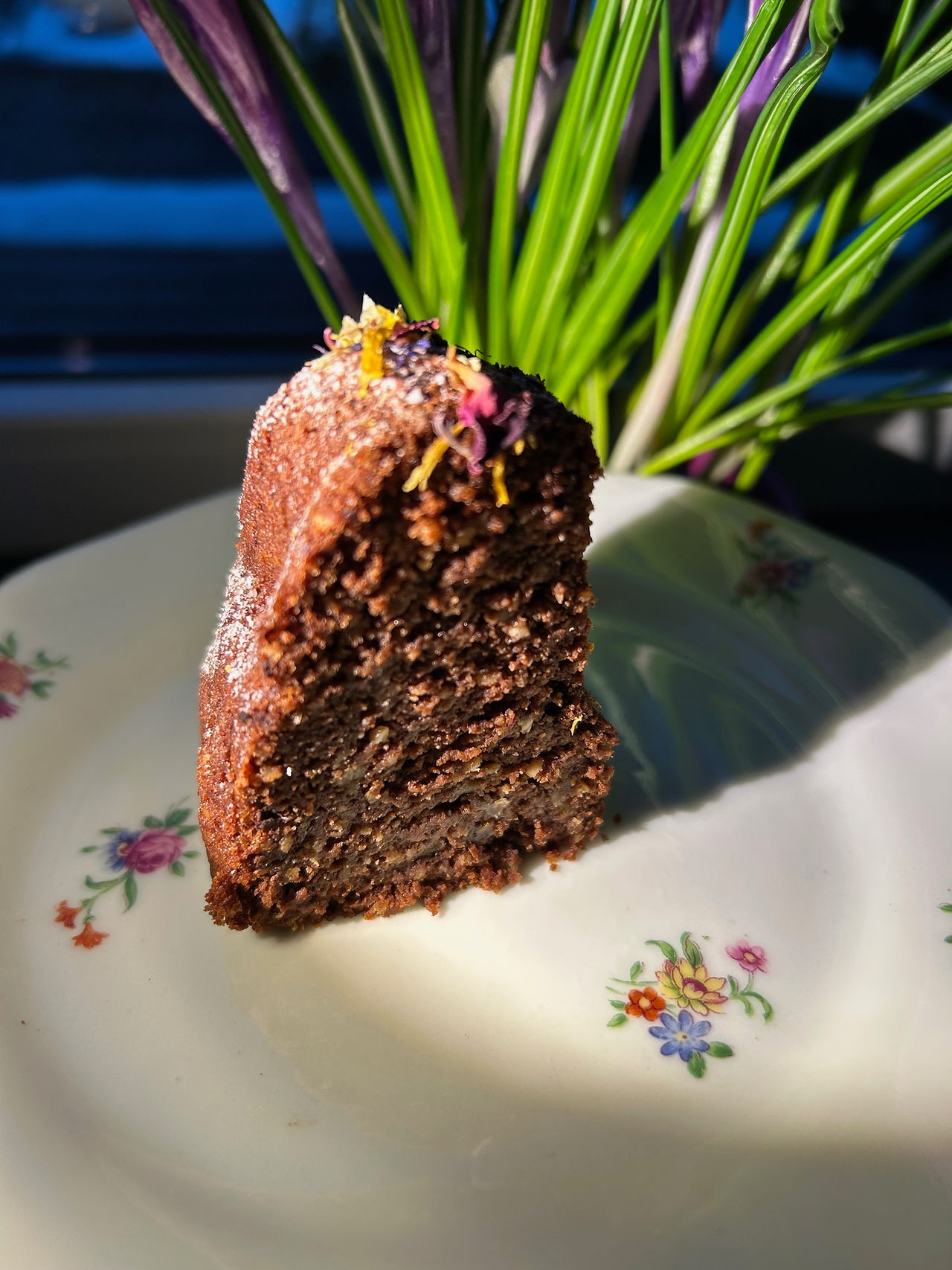 Angeschnittenes Stück veganer Brownie-Gugelhupf mit dichter, saftiger Krume, serviert auf einem Teller, Schokokuchen mit Kakao und Mandeln, brownieartige Textur gut sichtbar