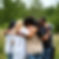 a groupe of 10-12 people hugging eachother in nature , no faces showing, mix of white and