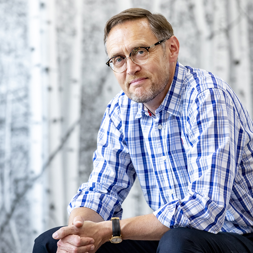 A Photograph of a man wearing a blue floral shirt