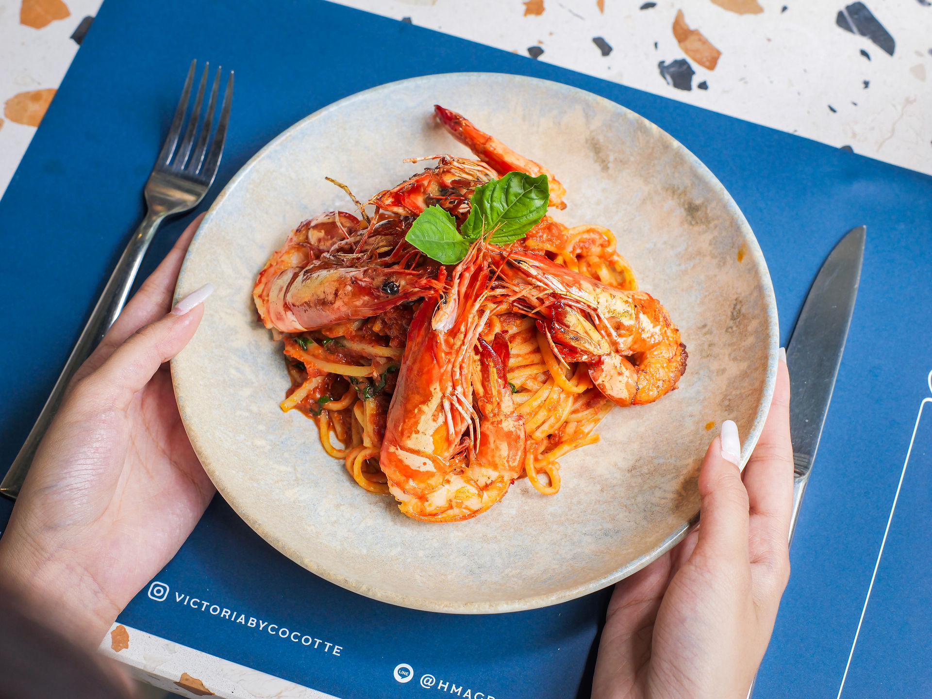 Someone holding a plate from top angle with Arrabbiata & Tiger Prawns