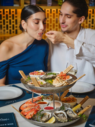 Seafood platter couple enjoying the platter together, the guy is feeding her a spoon of crab salad