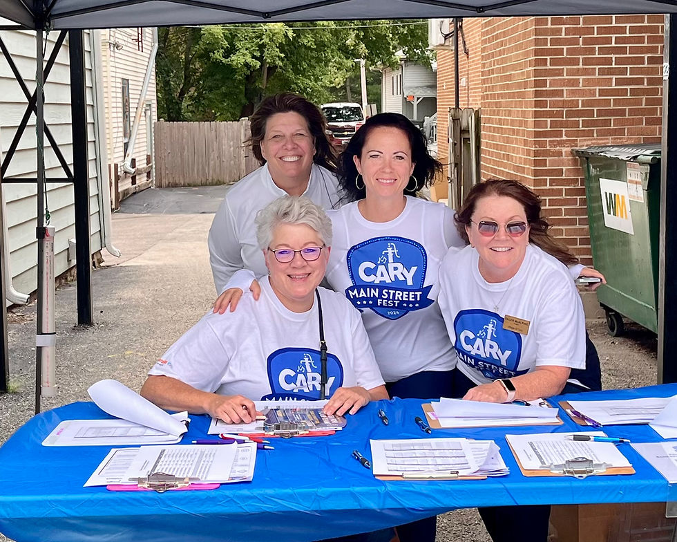Group of volunteers at the Cary Main Street Fest table smiling at the camera.