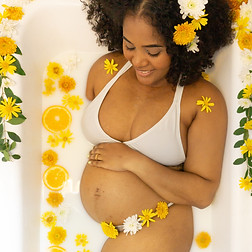 Ensaio Gestante, com grávida em uma banheira de leite rodeada de flores e laranjas