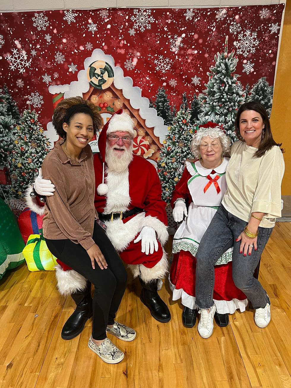Ms. Slay (3-5 Counselor) and Ms. Agostinelli (K-2 Counselor) smile with Mr. and Mrs. Claus at a PBIS party.