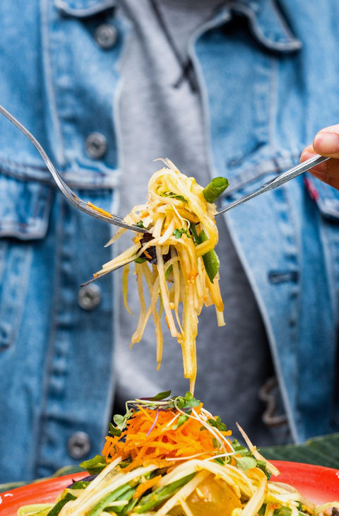 Person using forks to eat delicious Thai green papaya salad