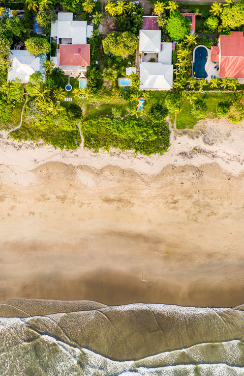 Aerial view of Playa Grande, Costa Rica, where waves embrace the shore, framed by lush foliage and villas like Villa Olivia. Perfect for a family vacation rental at the Gold Coast's serene escape.beach and turquoise ocean.
