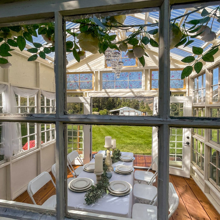A view toward a table set for a small group inside the Glasshouse.