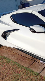 "274 Car Wash on the Spot detailer wiping down the windshield of a white Corvette C8 Stingray with a pink microfiber towel in a residential driveway."