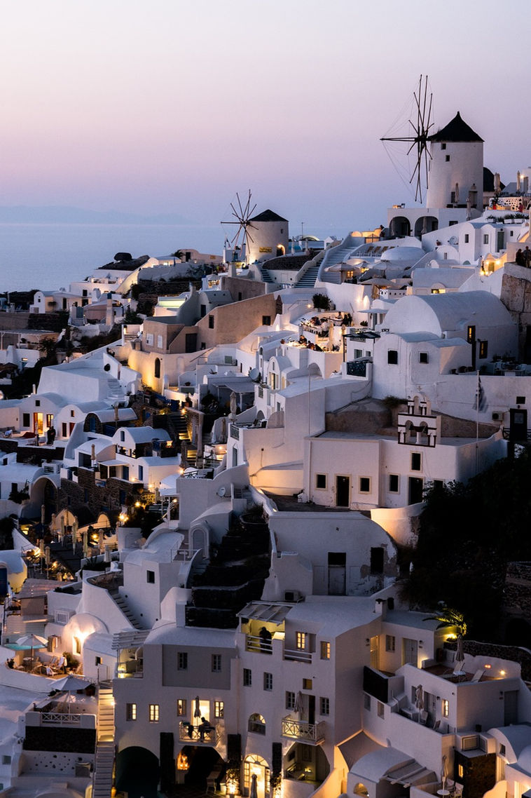Oia, Santorini lit up at dusk with the iconic windmill.
