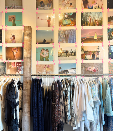 rack of vintage clothing with ashley sophia clark photography on wall behind it at fine art fruit shop in portland