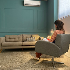 foto do consultório da psicóloga Bianca Miranda. A imagem a psicóloga sentada na poltrona de atendimento, lendo