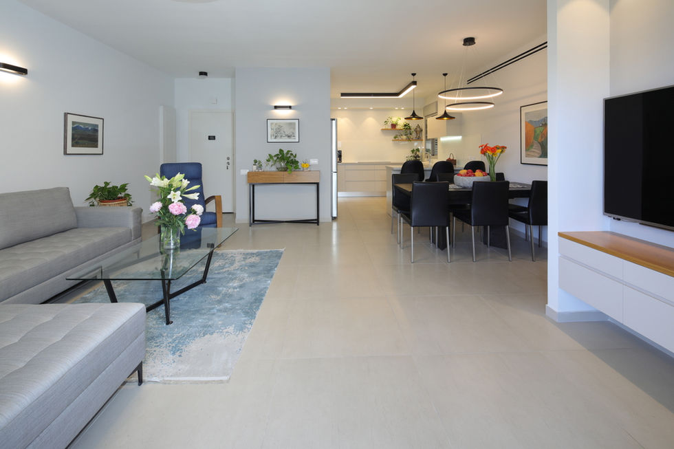   עיצוב פנים מודרני לחלל מגורים פתוח הכולל סלון מואר, פינת אוכל מעוצבת ומטבח בהיר בקווים נקיים.