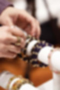 main d'une femme avec des bagues entreposant des bracelets en pierres précieuses sur un présentoir