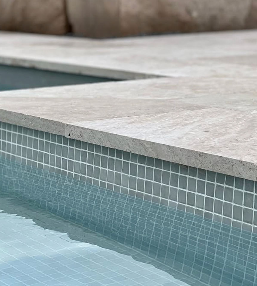 Premium pool coping and ivory travertine detailing on a luxury concrete pool